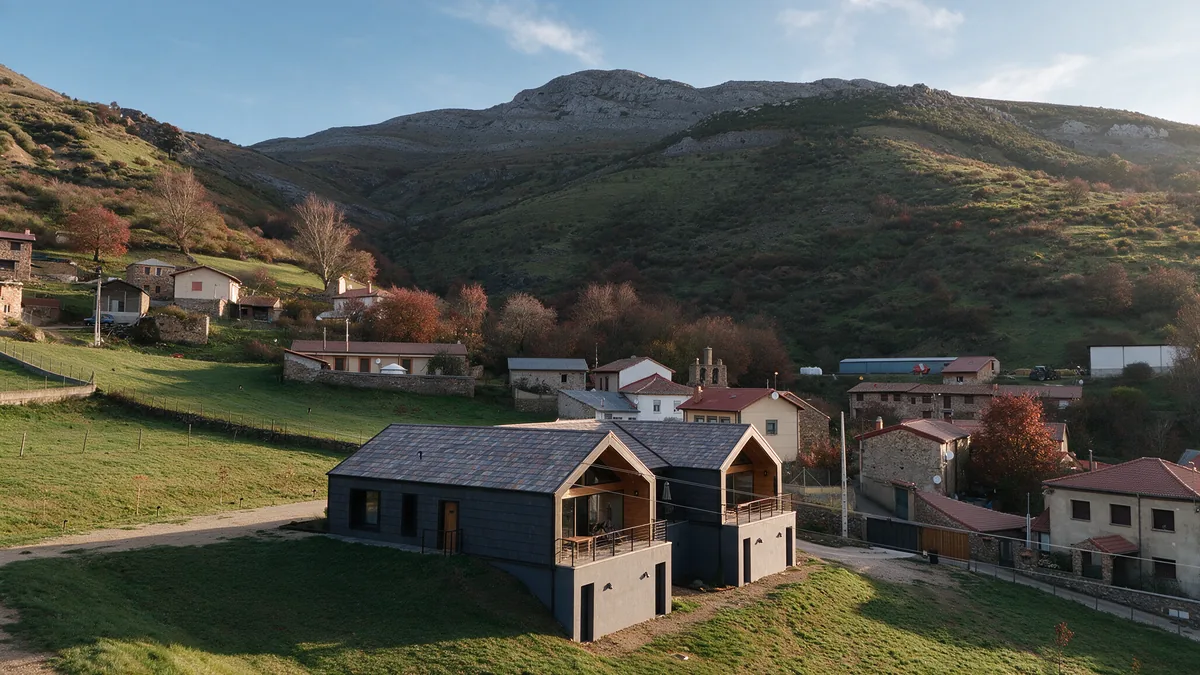 Vista aérea en otoño de las tres casas de La Finca del Valle sobre el prado, con el Valle de Vegacervera y la montaña de León detrás
