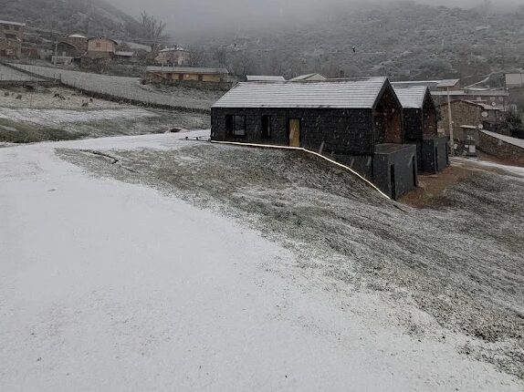 Las casas de La Finca del Valle nevadas en el Valle de Vegacervera, con el pueblo y la ladera cubiertos de nieve, León